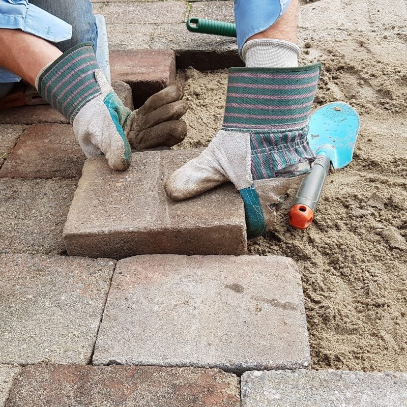 Stratenmaker legt klinker neer op zandbed