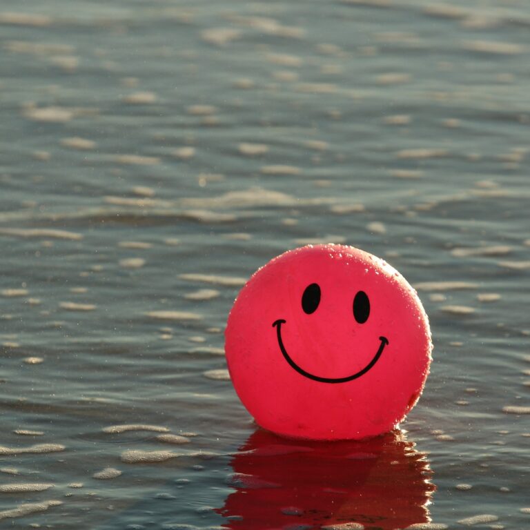 Drijvende rode bal met lachende smiley drijvend in het water